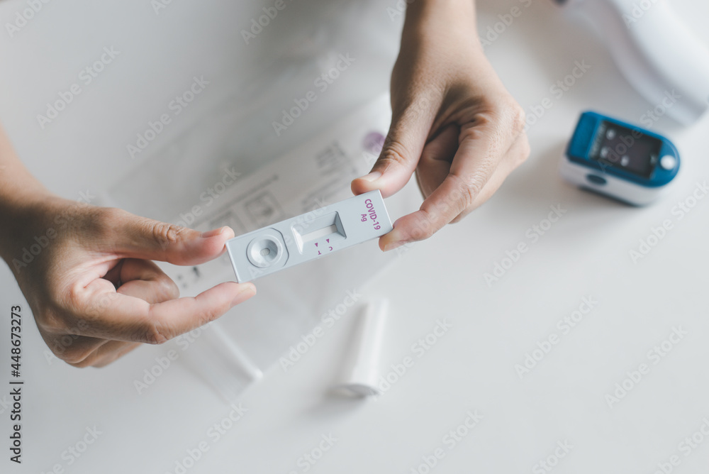 Patient woman using a covid-19 self test rapid antigen testing kit at home Patient woman using a covid-19 self test rapid antigen testing kit at home
