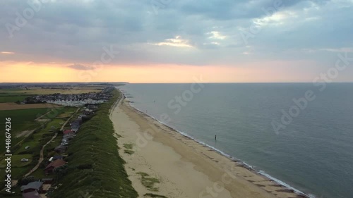 Aerial: Eccles sea beach with fishing village at Norfolk, England - tilt up shot photo