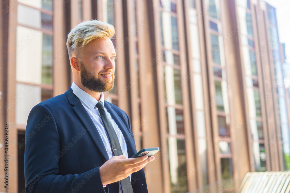 Confident businessman in front of modern office building. Financial investor is using smartphone outdoor. Banking and business. Confident businessman in front of modern office building. Financial investor is using smartphone outdoor. Banking and business.