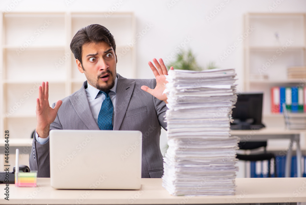 Young male employee unhappy with excessive work in the office Young male employee unhappy with excessive work in the office