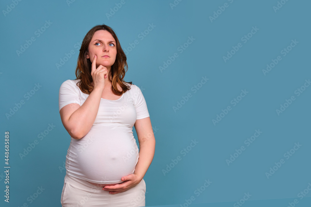 Portrait of a sad pregnant woman looking away on a blue background Portrait of a sad pregnant woman looking away on a blue background