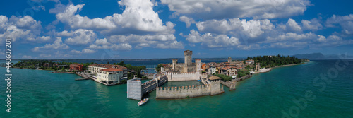 Italian castles Scaligero on the water. Aerial panorama of Sirmione castle, Lake Garda, Italy. Flag of Italy on the towers of the castle on Lake Garda. Top view of the 13th century castle.