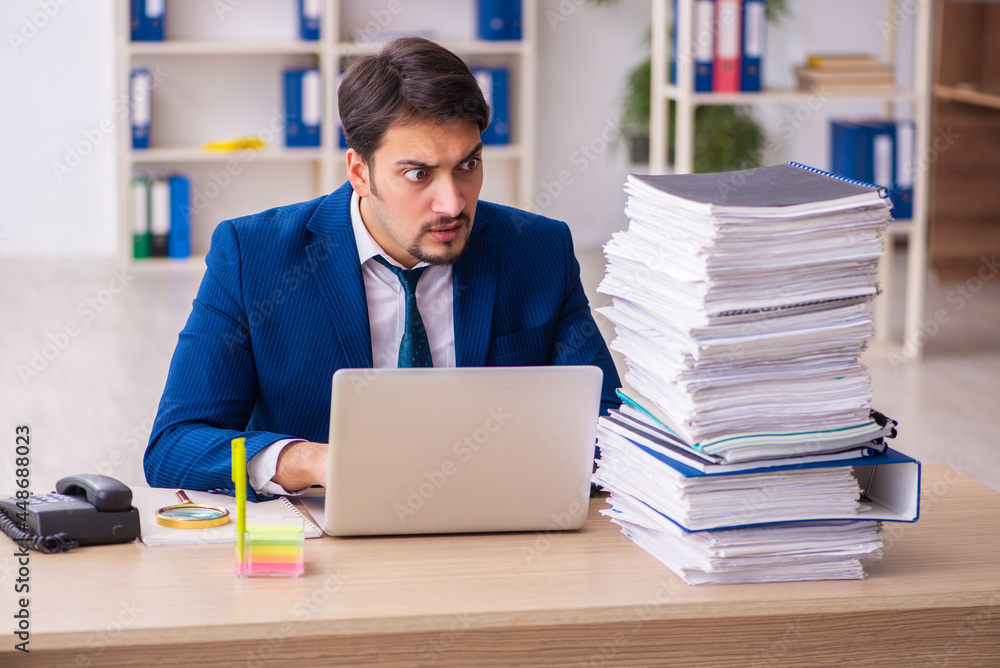 Young male employee and too much work in the office Young male employee and too much work in the office