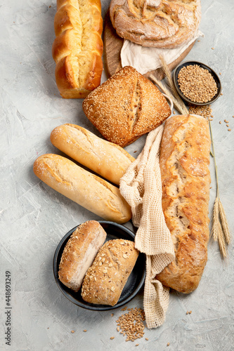 Various types of fresh baked bread on light gray background.