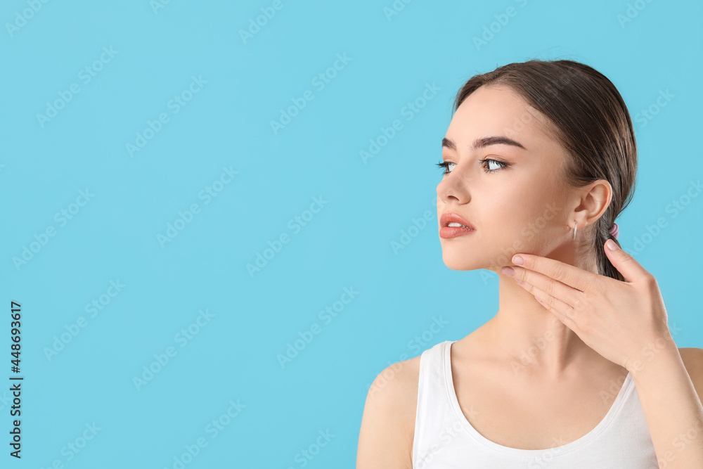 Beautiful young woman massaging her face on color background Beautiful young woman massaging her face on color background