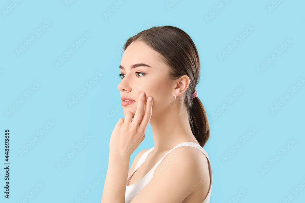 Beautiful young woman massaging her face on color background Beautiful young woman massaging her face on color background
