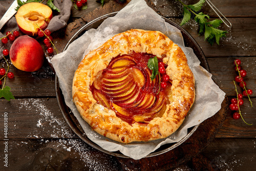 Peach gallete on baking paper on wooden background. Freshly prepared homemade pie. photo