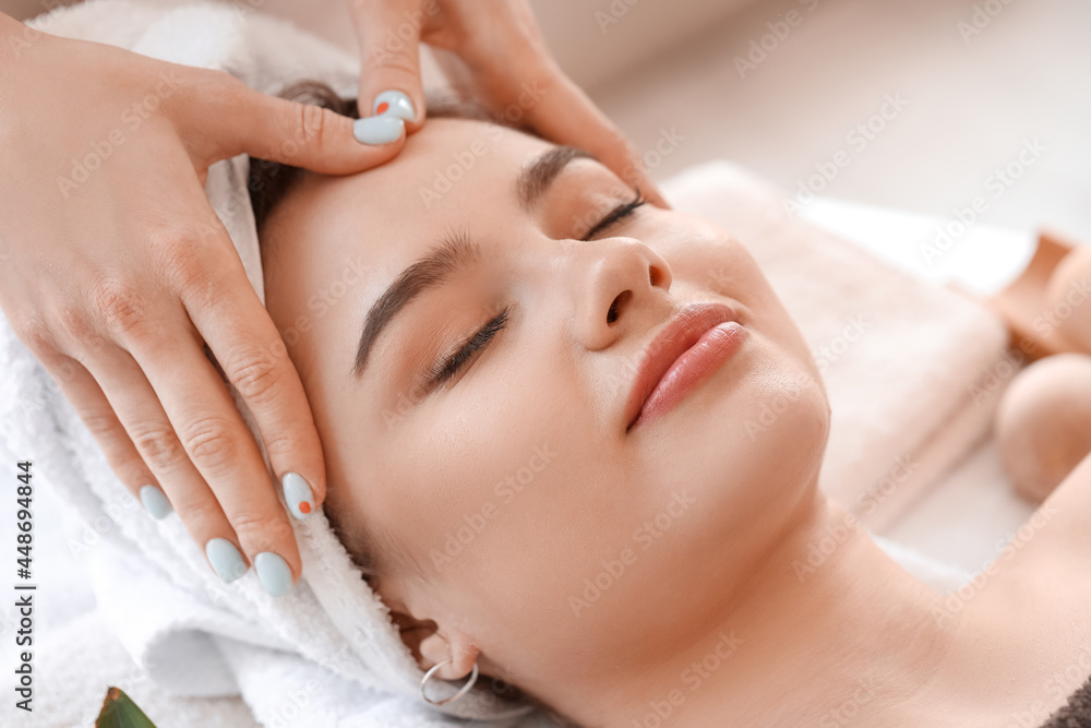 Young woman receiving face massage in beauty salon