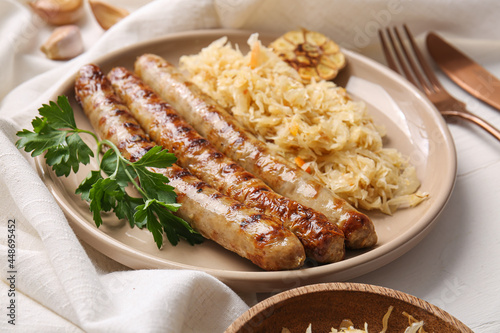 Plate with tasty sauerkraut and grilled sausages on table