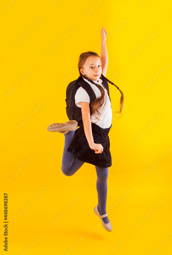 Jumping emotional schoolgirl on the yellow background Jumping emotional schoolgirl on the yellow background