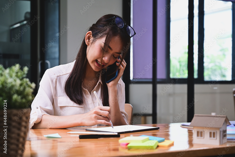 Smiling young woman talking on mobile phone and using digital tablet. Smiling young woman talking on mobile phone and using digital tablet.