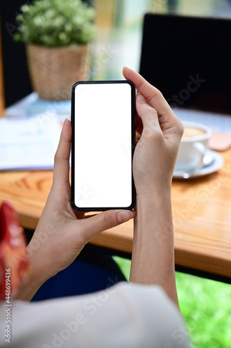 Close up view woman holding smart phone with white screen.