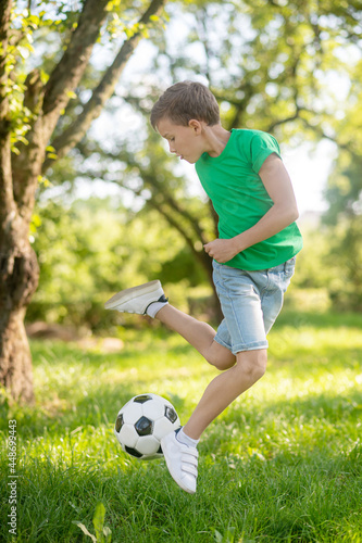 Boy jumping with soccer ball in nature