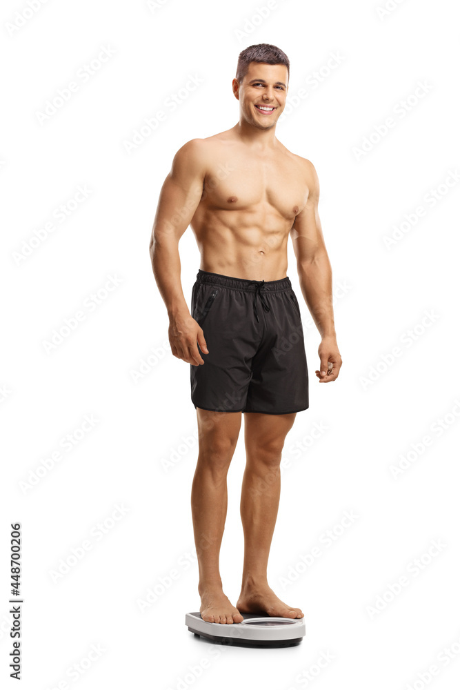 Fototapeta premium Full length shot of a shirtless young man standing on a weight scale and looking at camera
