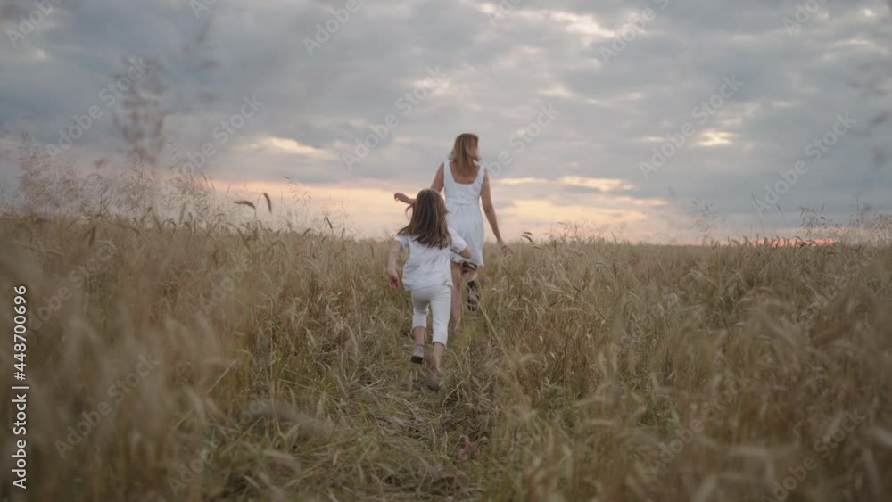 follow :Daughter and mother dream together run in the wheat field at sunset. happy family people in the wheat field concept. Mom and girl playing catch-up run. baby child fun running in green meadow. 