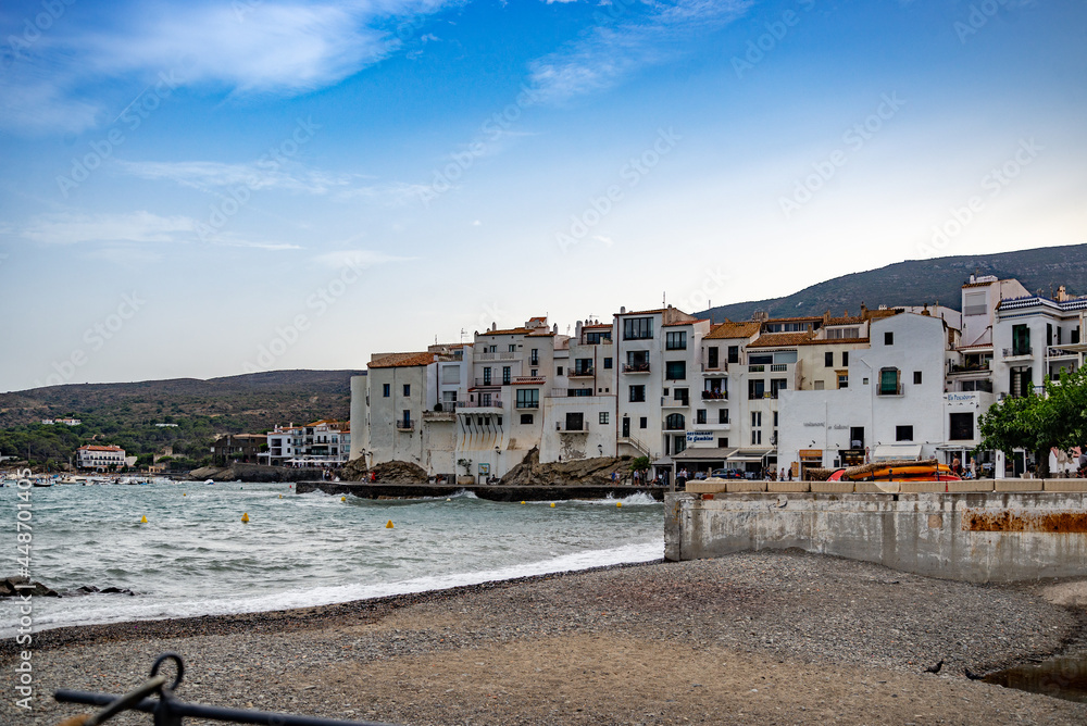 Casas blancas y mar azul en el puerto de Cadaqués con la iglesia y la playa, Costa Brava, España