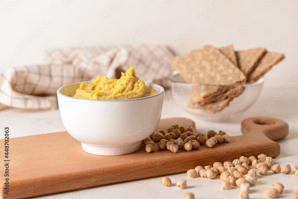 Bowl with tasty hummus, chickpeas and crackers on light background, closeup Bowl with tasty hummus, chickpeas and crackers on light background, closeup