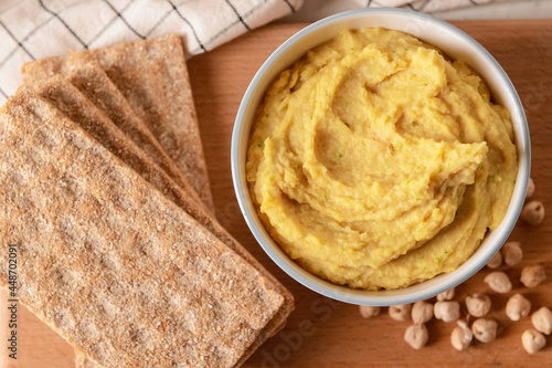 Bowl with tasty hummus, chickpeas and crackers on table, closeup