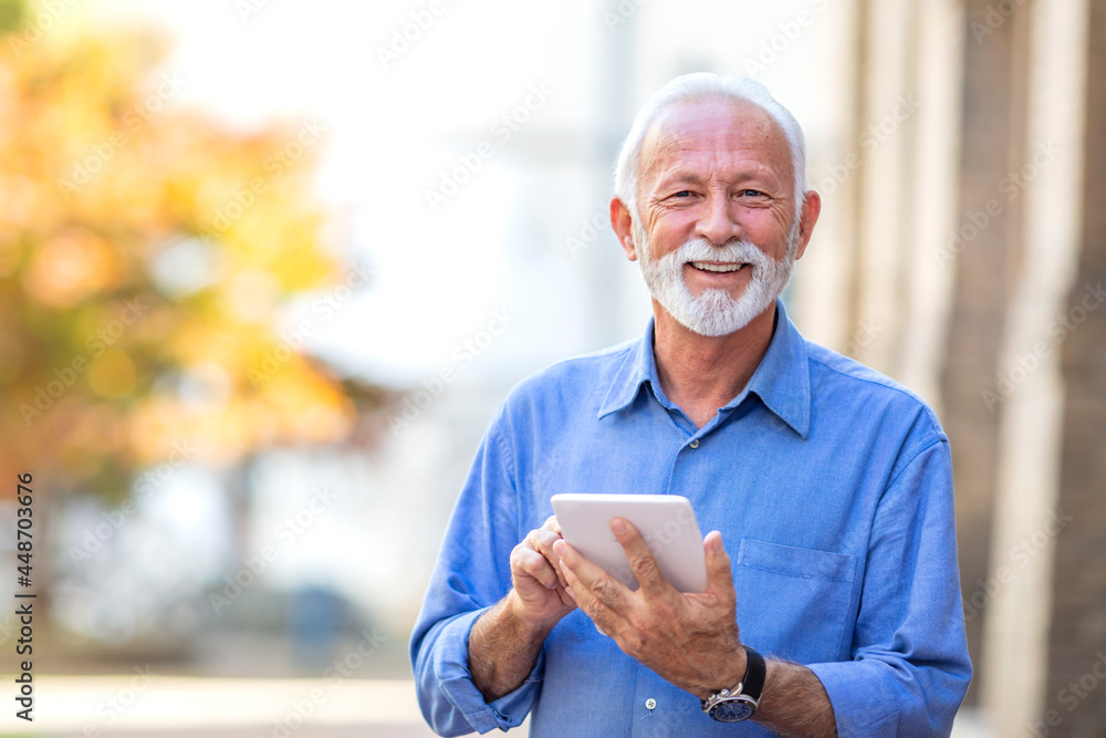 Handsome senior man with tablet in the street. Man using tablet in the public park. Senior businessman using a tablet in the city. Successful Modern Mature Businessman Handsome senior man with tablet in the street. Man using tablet in the public park. Senior businessman using a tablet in the city. Successful Modern Mature Businessman