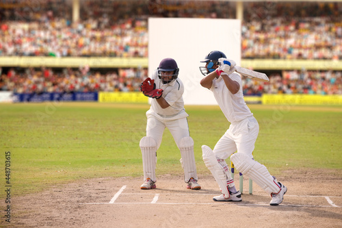 Cricketer batsman hitting a shot during a match on the pitch photo