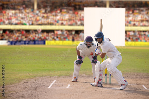 Obraz na płótnie Cricketer batsman hitting a shot during a match on the pitch