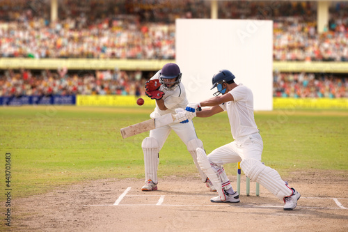 Cricketer batsman hitting a shot during a match on the pitch