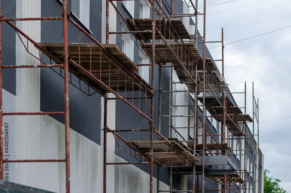 Scaffolding against Dark gray building with white windows. Beaut Scaffolding against Dark gray building with white windows. Beaut