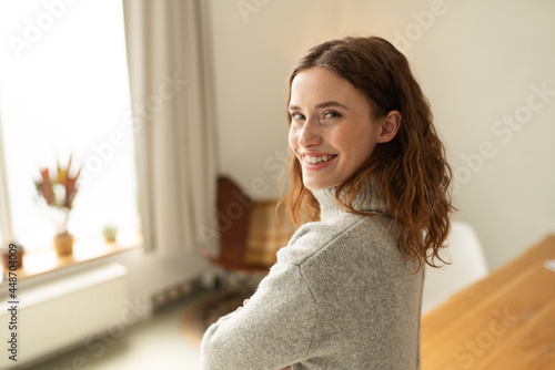 Friendly young woman looking back over her shoulder at camera