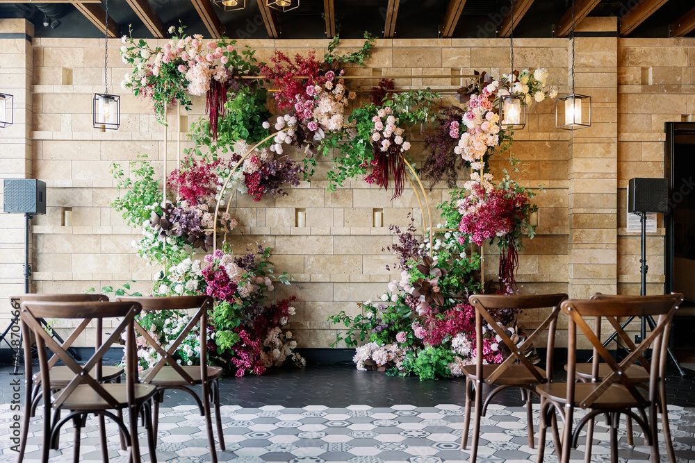 wedding arch at the restaurant with red flowers and wooden chairs