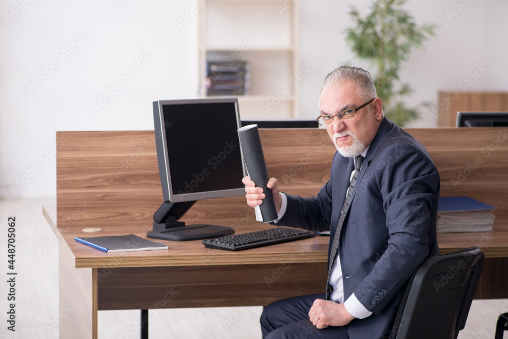 Aged male employee sitting at workplace Aged male employee sitting at workplace