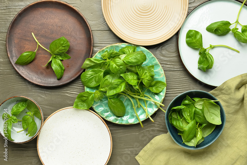 Plates with fresh basil leaves on wooden background