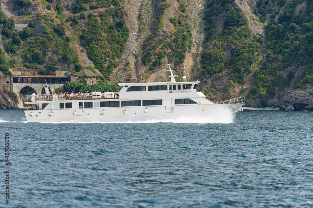White ferry boat with tourists in motion in front of the eroded coast of the Cinque Terre National Park, UNESCO world heritage site, Ligurian Sea, La Spezia, Liguria, Italy, Europe. White ferry boat with tourists in motion in front of the eroded coast of the Cinque Terre National Park, UNESCO world heritage site, Ligurian Sea, La Spezia, Liguria, Italy, Europe.