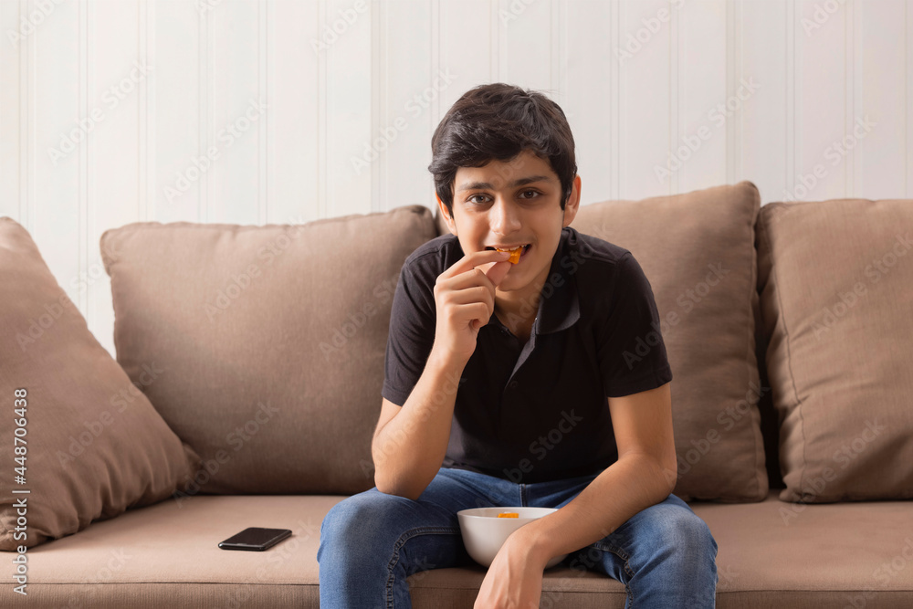 A SMART TEENAGER SITTING AND EATING SNACKS AT HOME A SMART TEENAGER SITTING AND EATING SNACKS AT HOME
