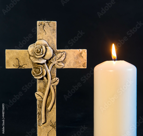 Isolated ornate religious cross with  burning candle on a dark background. Moment of grief at the end of a life.Sympathy card. photo