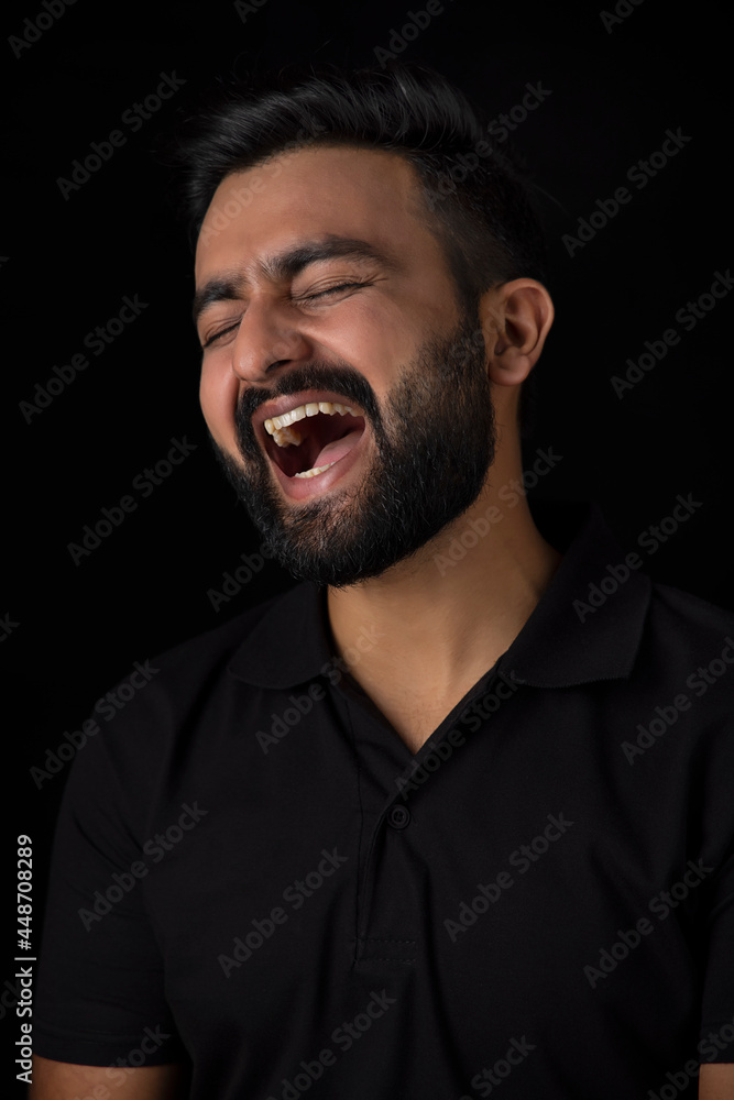 Fototapeta premium A BEARDED YOUNG MAN HEARTILY LAUGHING