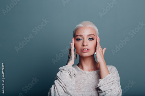 Millenial young woman with short blonde hair portrait doing face yoga self facebuilding massage for skin photo