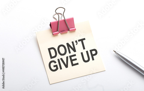 Don't Give Up text on sticker with pen on the white background