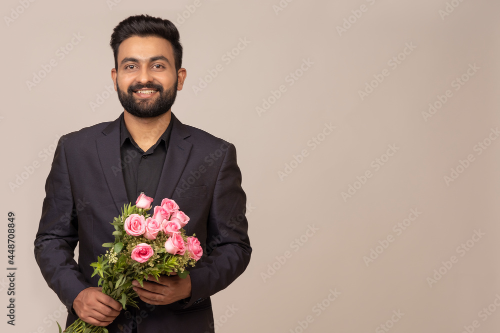 PORTRAIT OF A BEARDED YOUNG MAN STANDING WITH BOUQUET IN HAND PORTRAIT OF A BEARDED YOUNG MAN STANDING WITH BOUQUET IN HAND