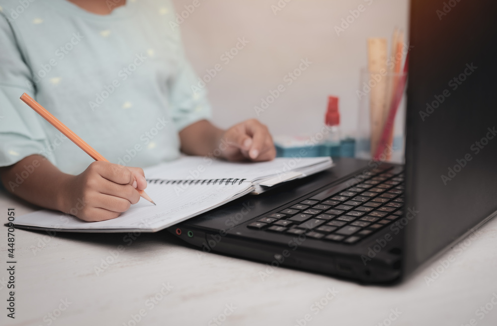 Young kid girl studying at home using a computer notebook laptop at home , education concept. Young kid girl studying at home using a computer notebook laptop at home , education concept.
