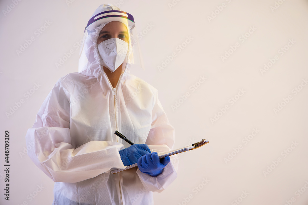 A health worker in PPE kit holding a notepad and pen. A health worker in PPE kit holding a notepad and pen.
