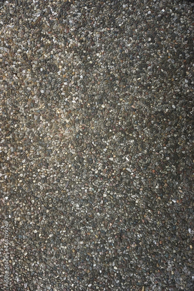 Rough grainy stone pebble pavement abstract vertical monochromatic gray background texture Rough grainy stone pebble pavement abstract vertical monochromatic gray background texture