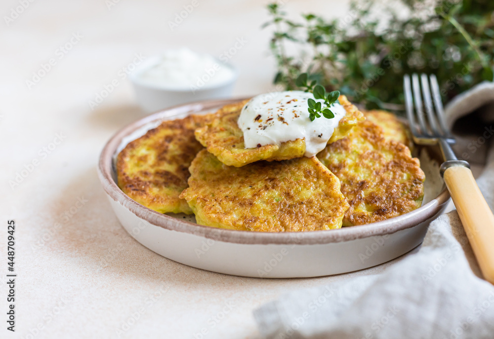 Vegetable fritters or pancakes with yoghurt or cream sour dressing and herbs. Cabbage or zucchini fritters on ceramic plate. Healthy vegetarian food. Vegetable fritters or pancakes with yoghurt or cream sour dressing and herbs. Cabbage or zucchini fritters on ceramic plate. Healthy vegetarian food.