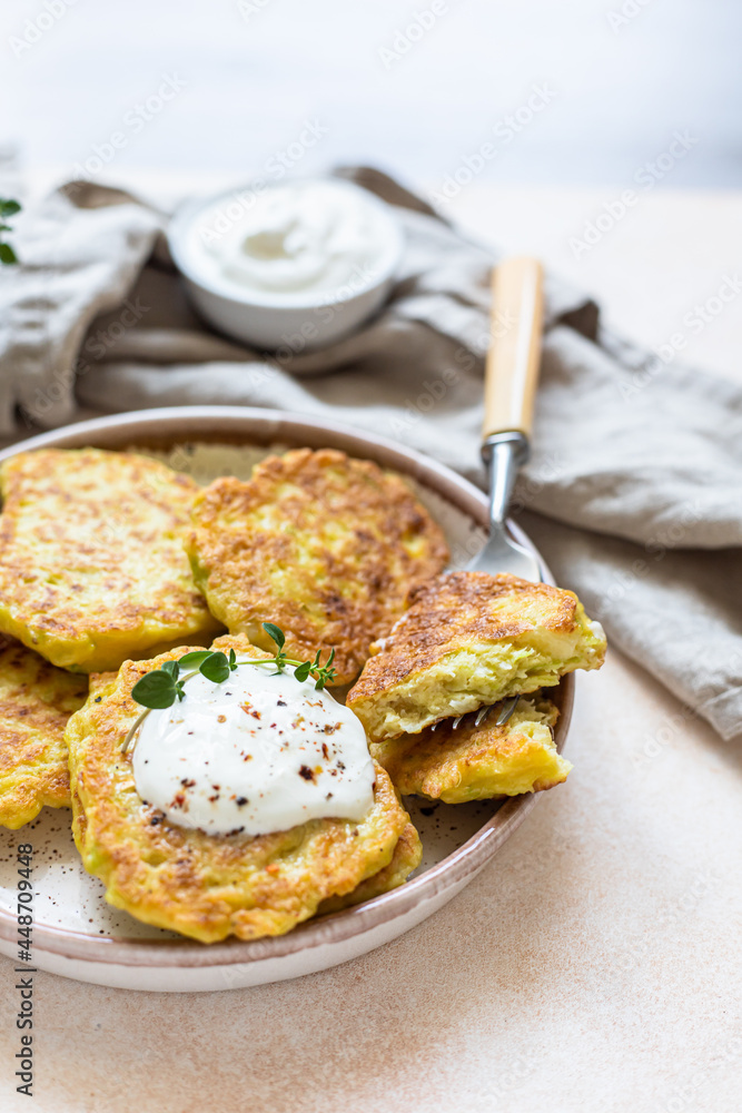 Vegetable fritters or pancakes with yoghurt or cream sour dressing and herbs. Cabbage or zucchini fritters on ceramic plate. Healthy vegetarian food. Vegetable fritters or pancakes with yoghurt or cream sour dressing and herbs. Cabbage or zucchini fritters on ceramic plate. Healthy vegetarian food.