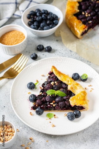 A piece of homemade galette with blueberries in a white plate on a culinary background close-up. Delicious sweet pastries