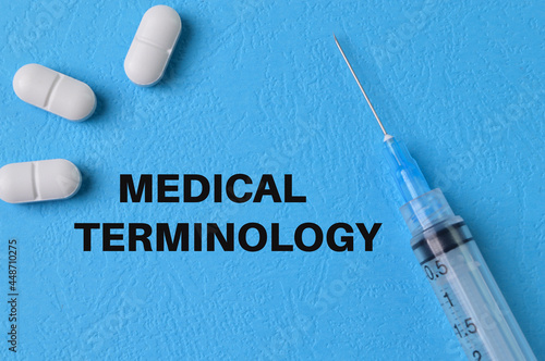 Syringe injection and pill capsules on blue background with text MEDICAL TERMINOLOGY photo