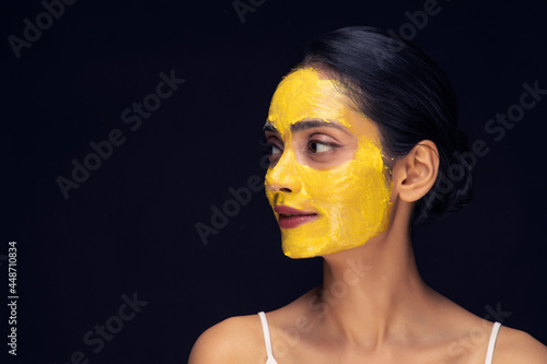 A young woman's face with home made face mask applied for skin care looking sideways. photo