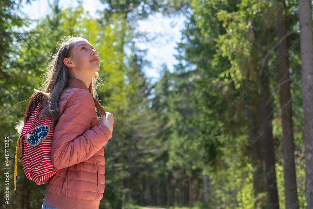 Pretty teen young tourist girl relaxing on forests road.Teenage with backpack on green forest summer or spring.Closeup. Pretty teen young tourist girl relaxing on forests road.Teenage with backpack on green forest summer or spring.Closeup.