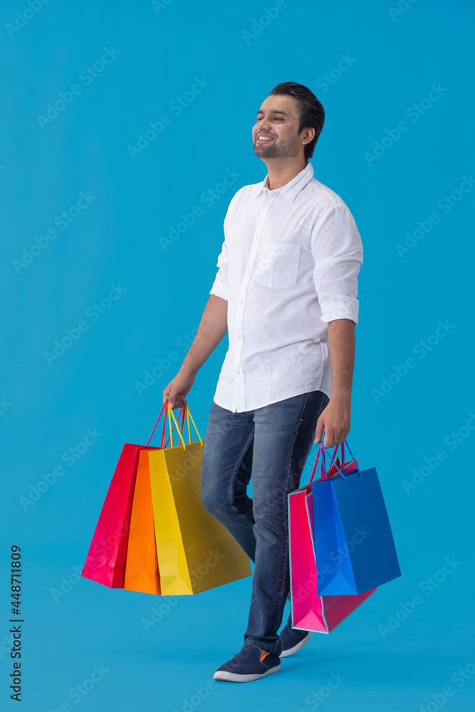 A young man standing with colorful carrybags in his hand. A young man standing with colorful carrybags in his hand.