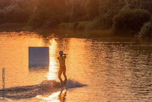 Man water wakeboarding skiing at sunset.
