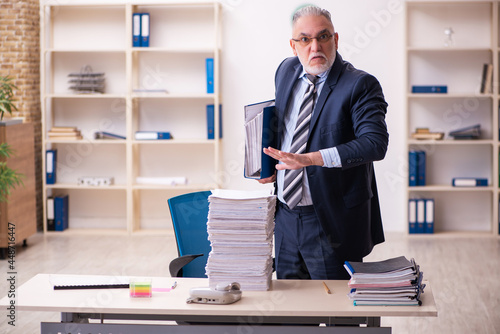 Old businessman employee unhappy with excessive work in the office